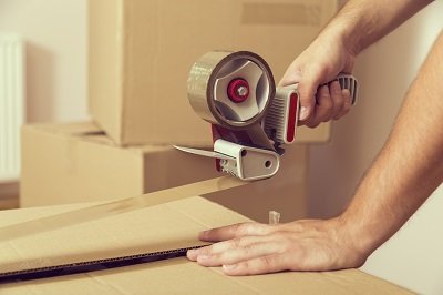 A hand taping up a cardboard box for removals.